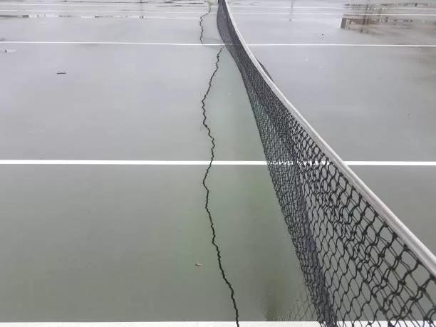 long crack or damaged on a wet tennis court with net