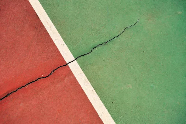 Weathered clay tennis court floor with a line and a crack
