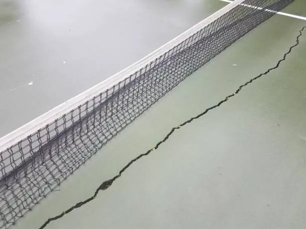 long crack or damaged on a wet tennis court with net