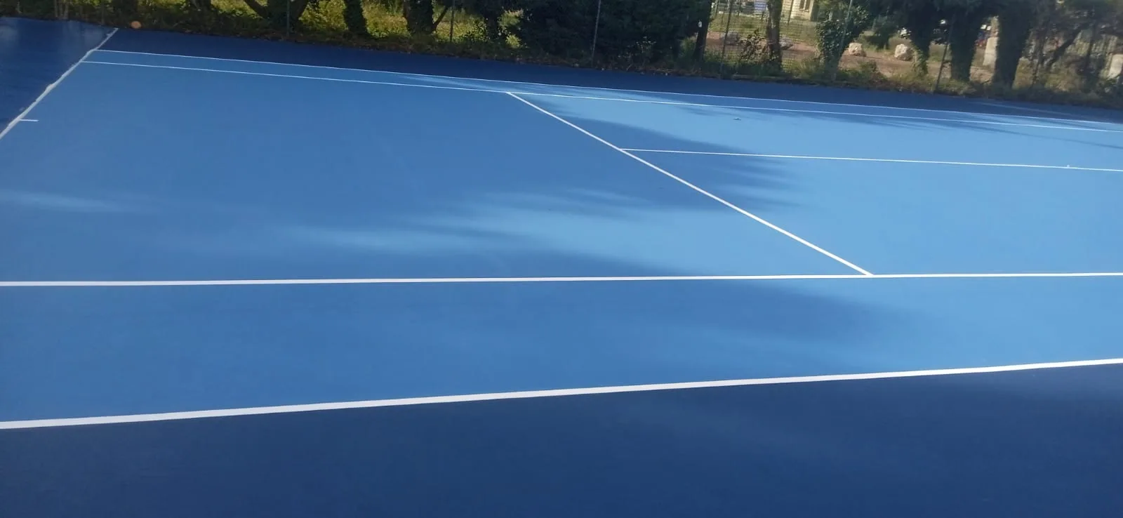 Court de tennis bleu aux lignes blanches neuves