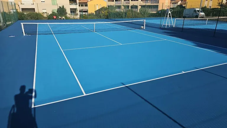 Court de tennis bleu clair et bleu foncé sous le soleil