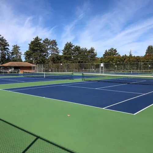 Court de tennis bleu marine et vert sous un ciel bleu