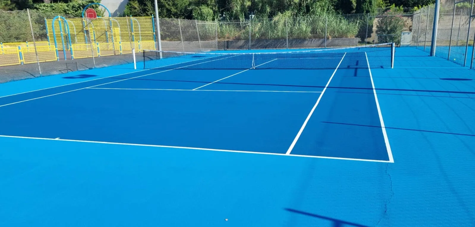 Court de tennis bleu vif clôturé