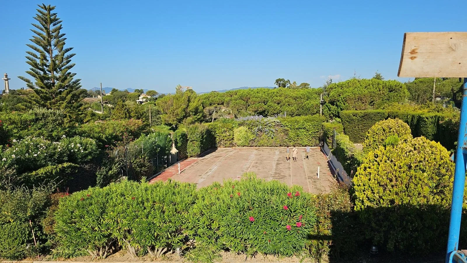 Court de tennis caché dans un jardin arboré