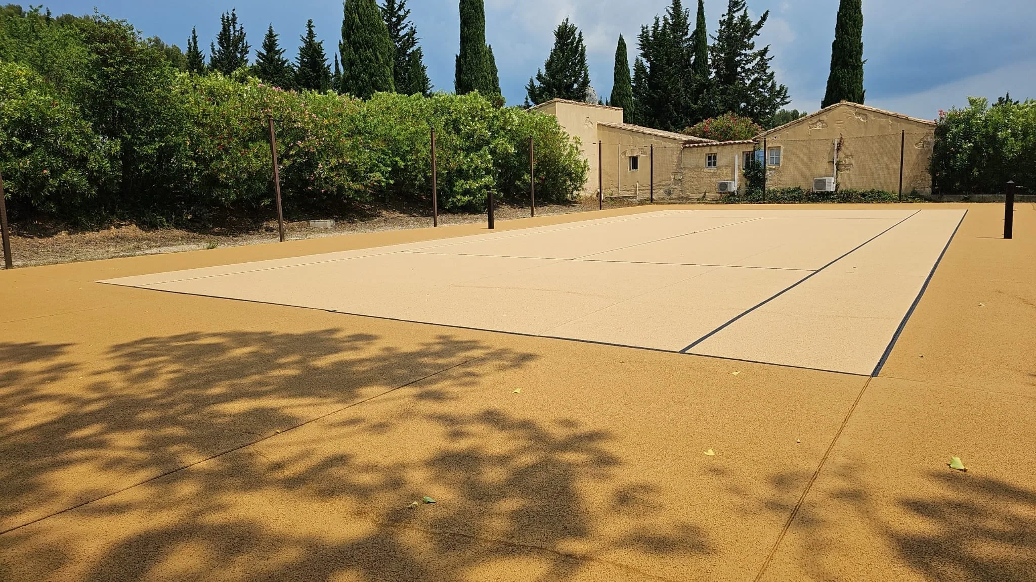 Court de tennis couleur sable devant une bâtisse provençale