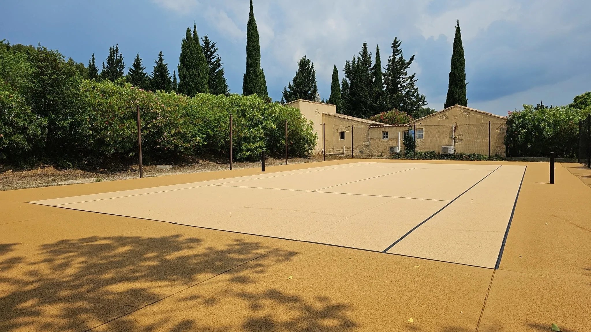 Court de tennis couleur sable devant une bâtisse provençale