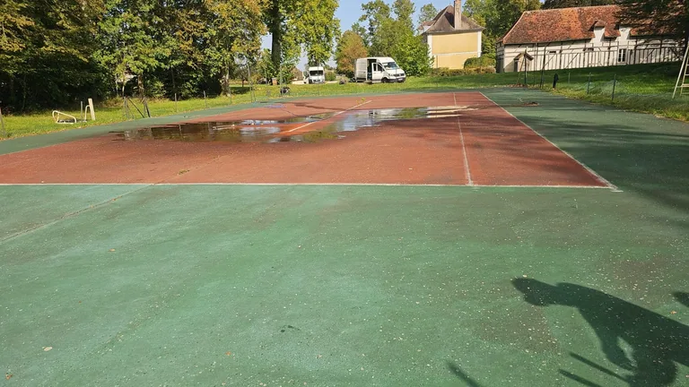 Court de tennis couvert de flaques d'eau après la pluie