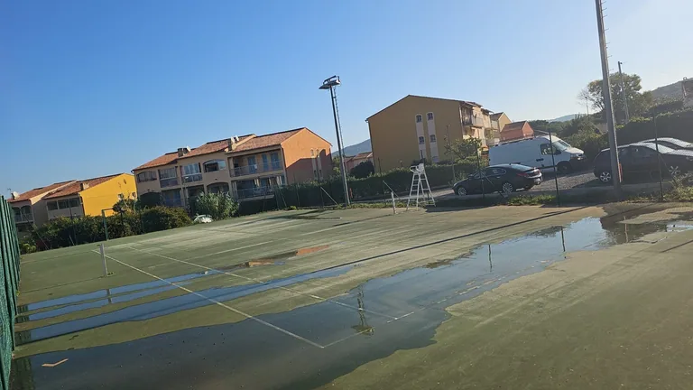 Court de tennis détrempé par les flaques avant reprise du drainage