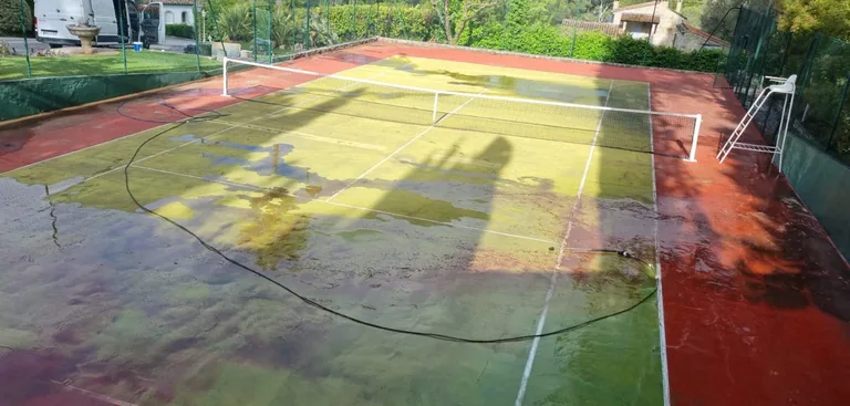 Court de tennis en cours de nettoyage, eau et mousse en surface