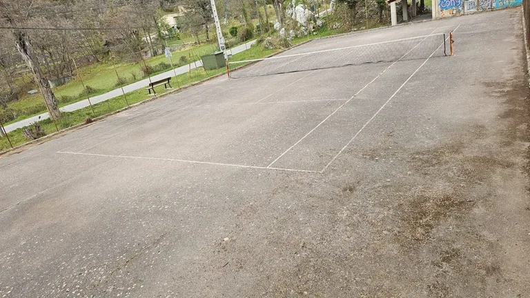 Court de tennis gris aux lignes effacées avant rénovation