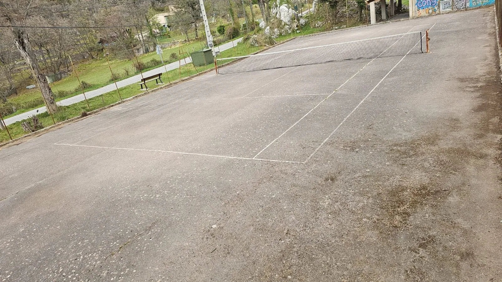 Court de tennis gris aux lignes effacées avant rénovation