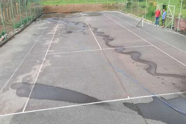 Court de tennis gris taché et fissuré avant rénovation