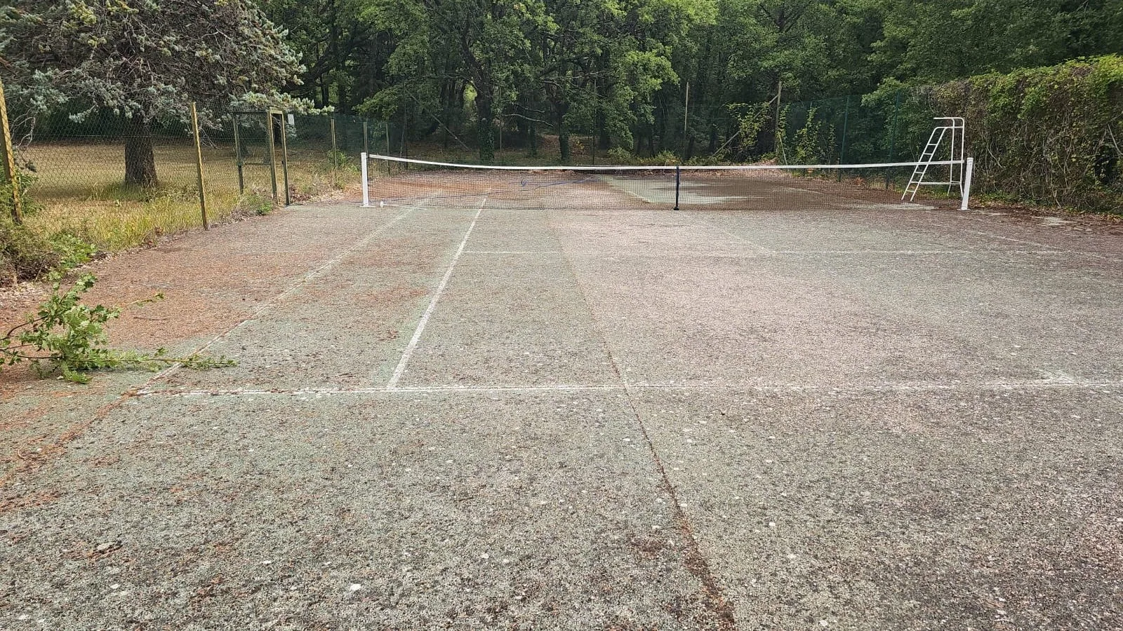 Court de tennis gris usé aux lignes effacées