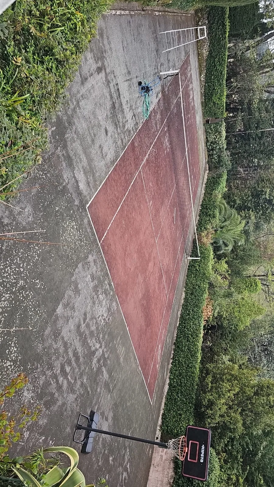 Court de tennis rouge abîmé et couvert de mousse