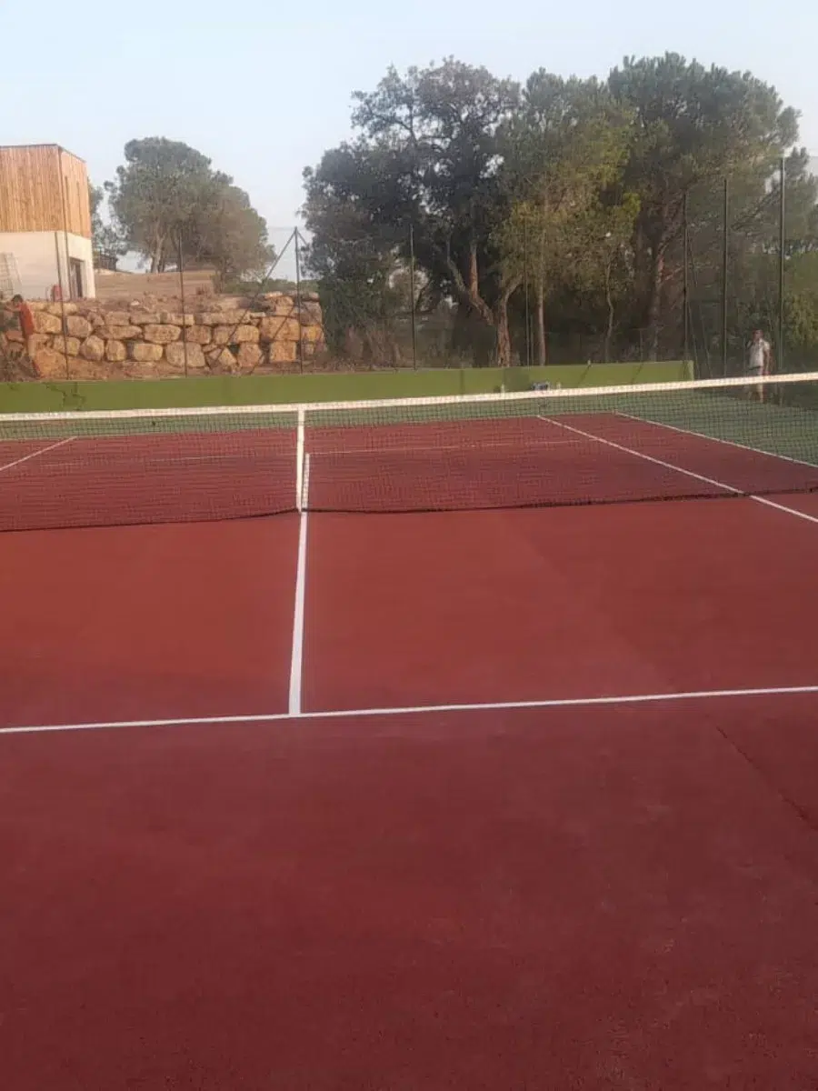 Court de tennis rouge en contrebas d'un mur de pierre