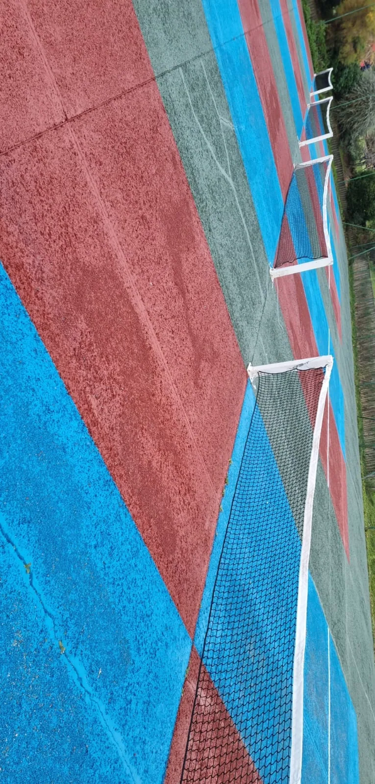 Court de tennis rouge et bleu vu de près, filet au premier plan