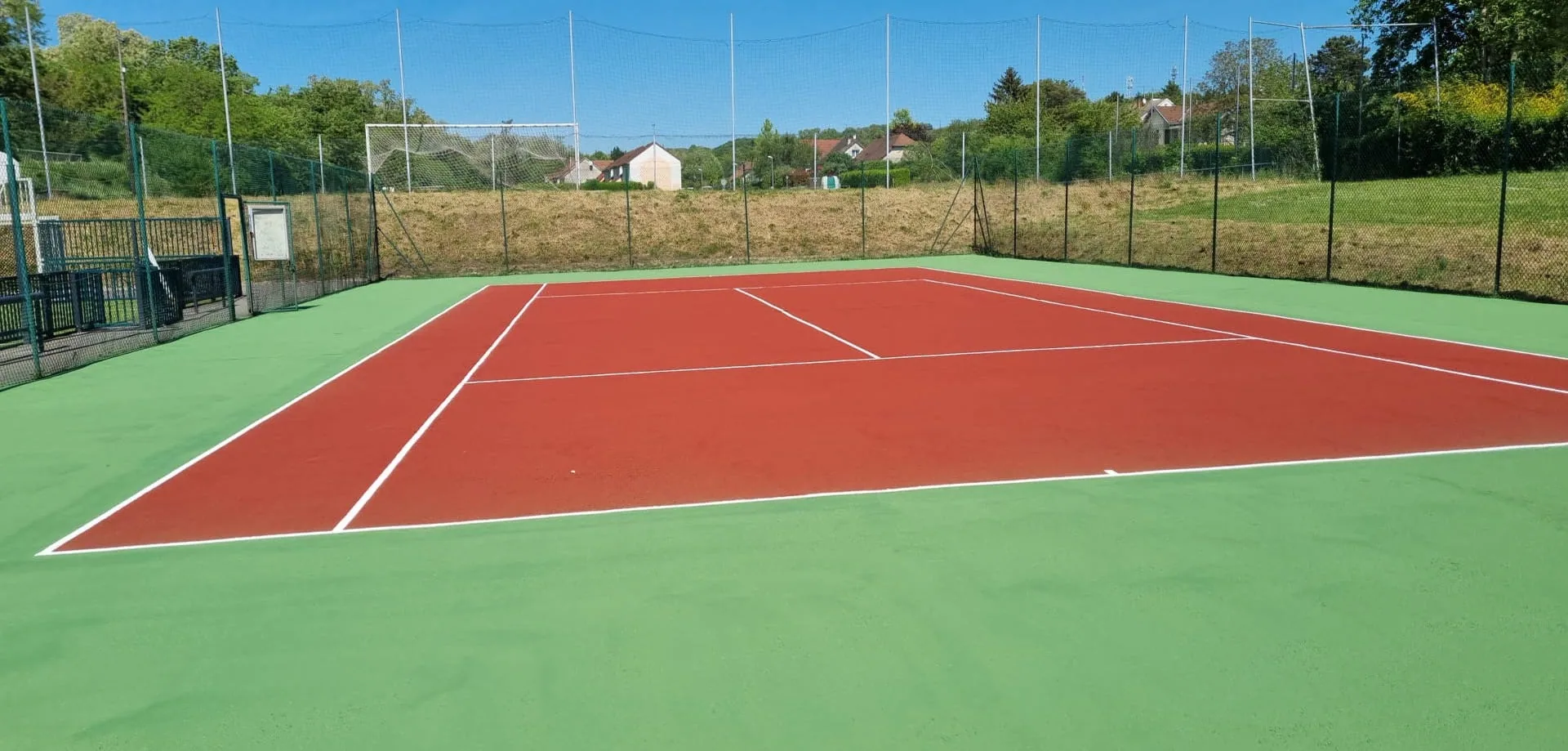 Court de tennis rouge et vert avec vue sur le village