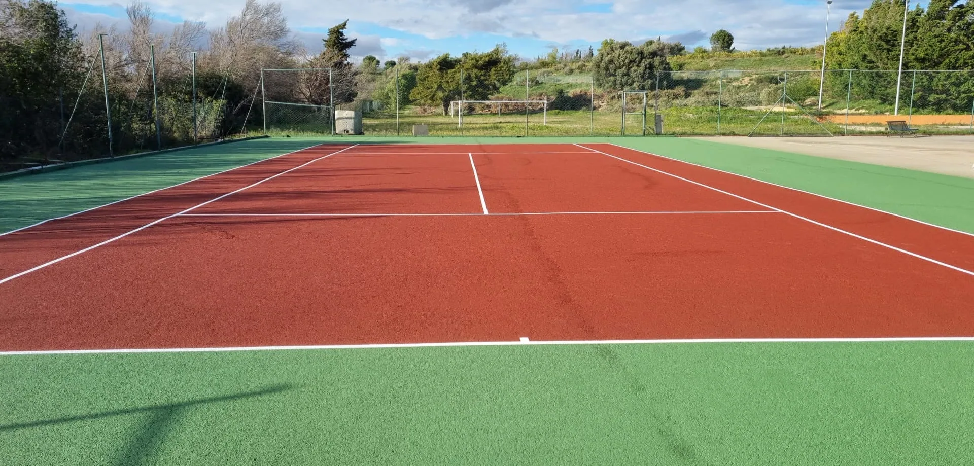 Court de tennis rouge et vert en milieu rural
