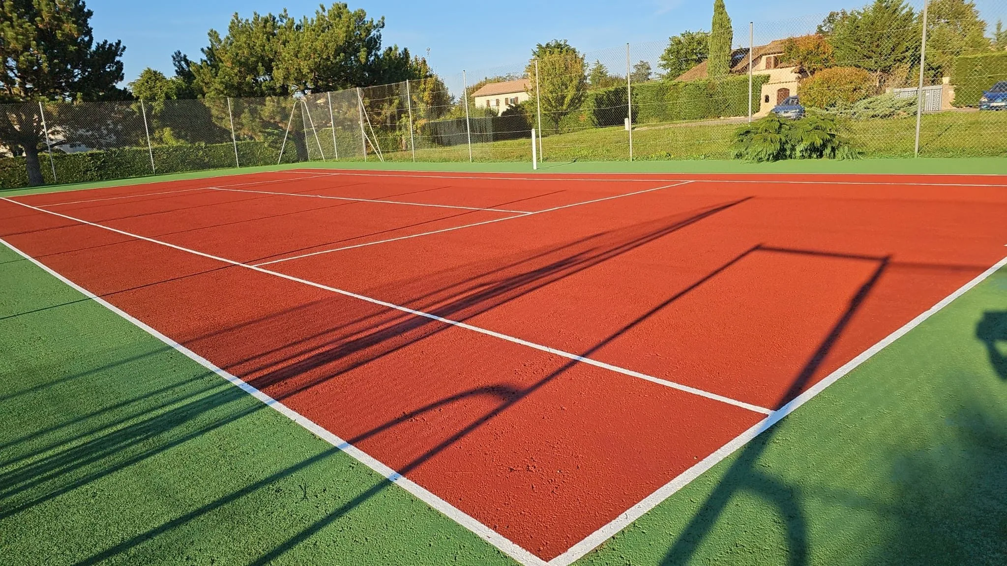 Court de tennis rouge et vert en plein soleil
