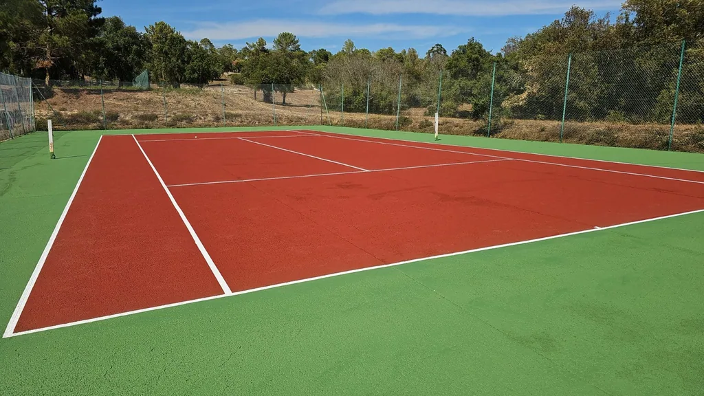 Court de tennis rouge et vert neuf sous un ciel bleu