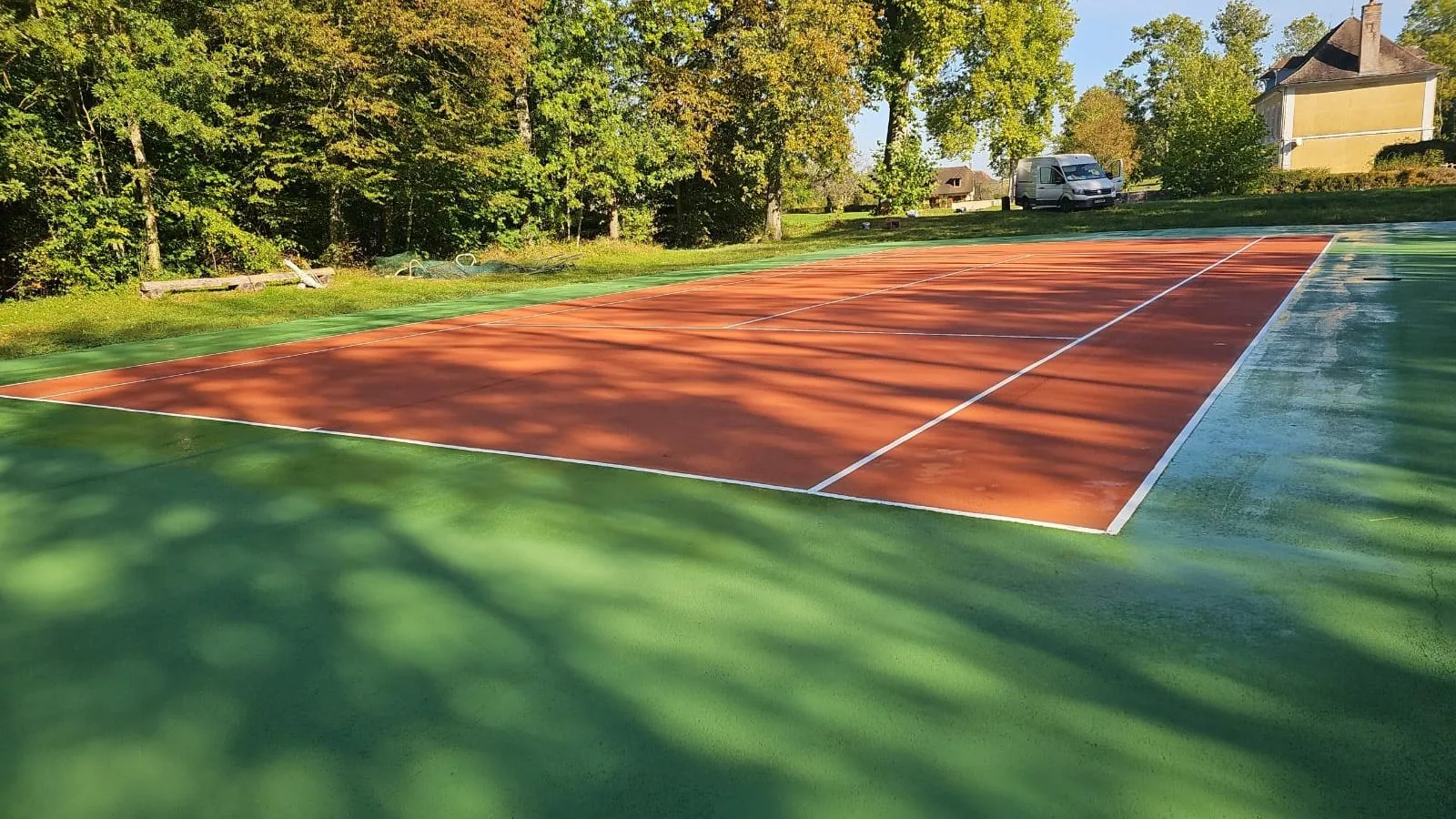 Court de tennis rouge et vert ombragé