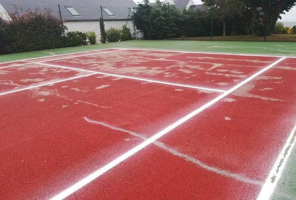 Court de tennis rouge fissuré avant rénovation