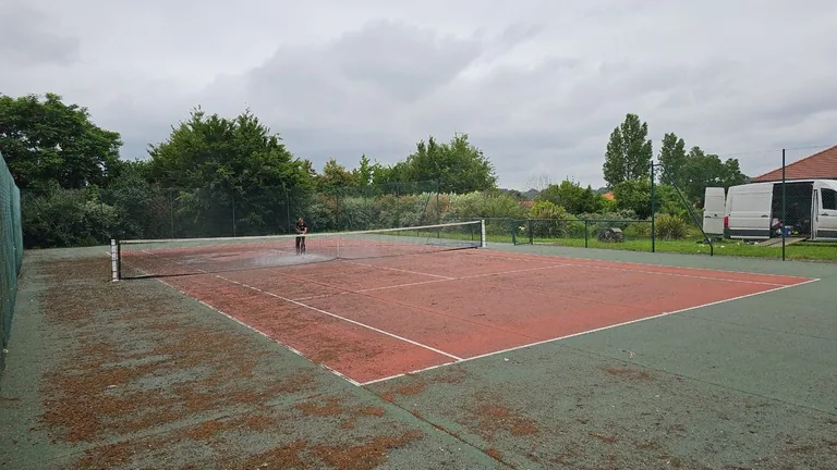 Court de tennis rouge usé et taché avant rénovation