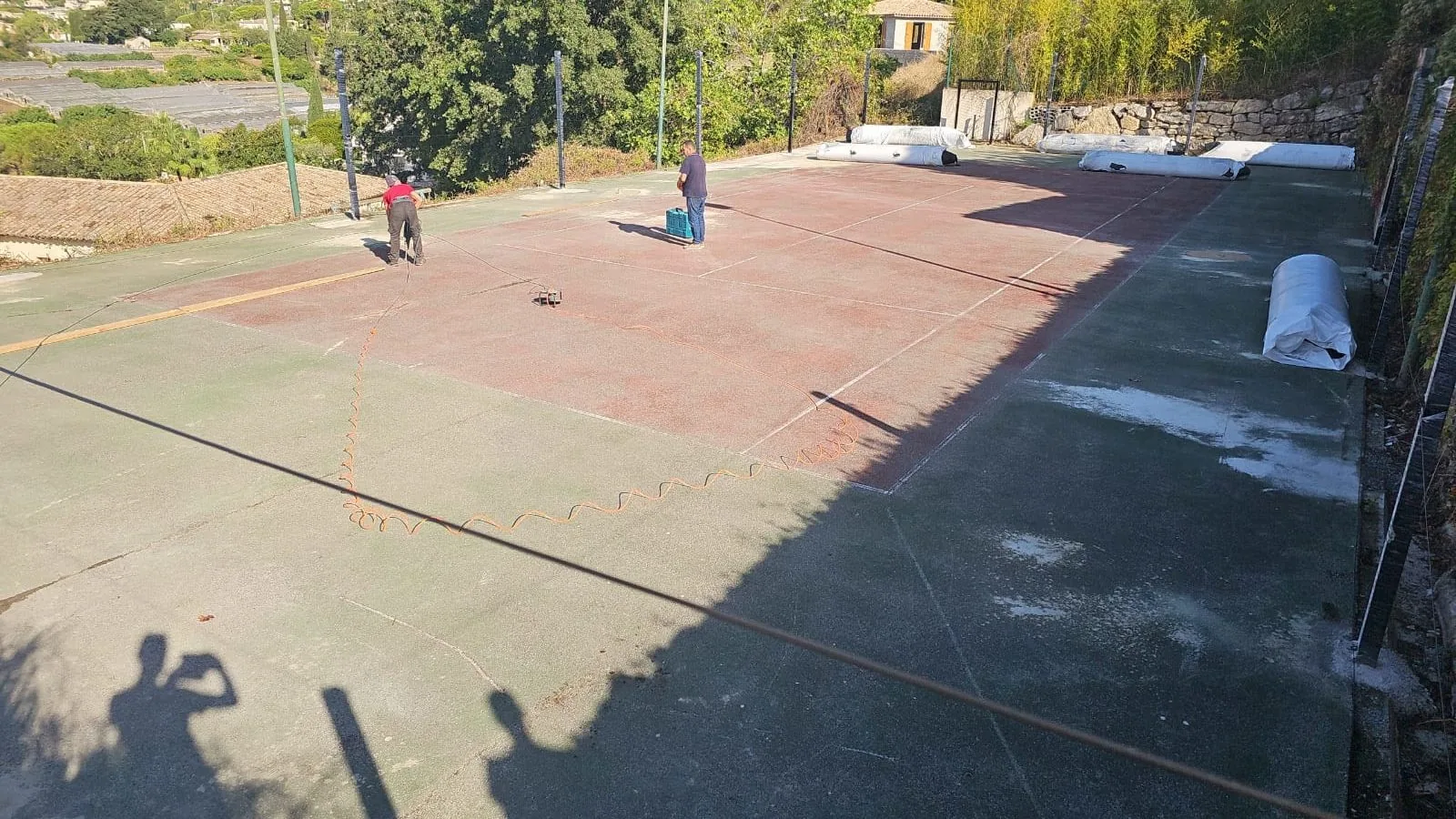 Court de tennis rouge usé pendant les travaux de rénovation