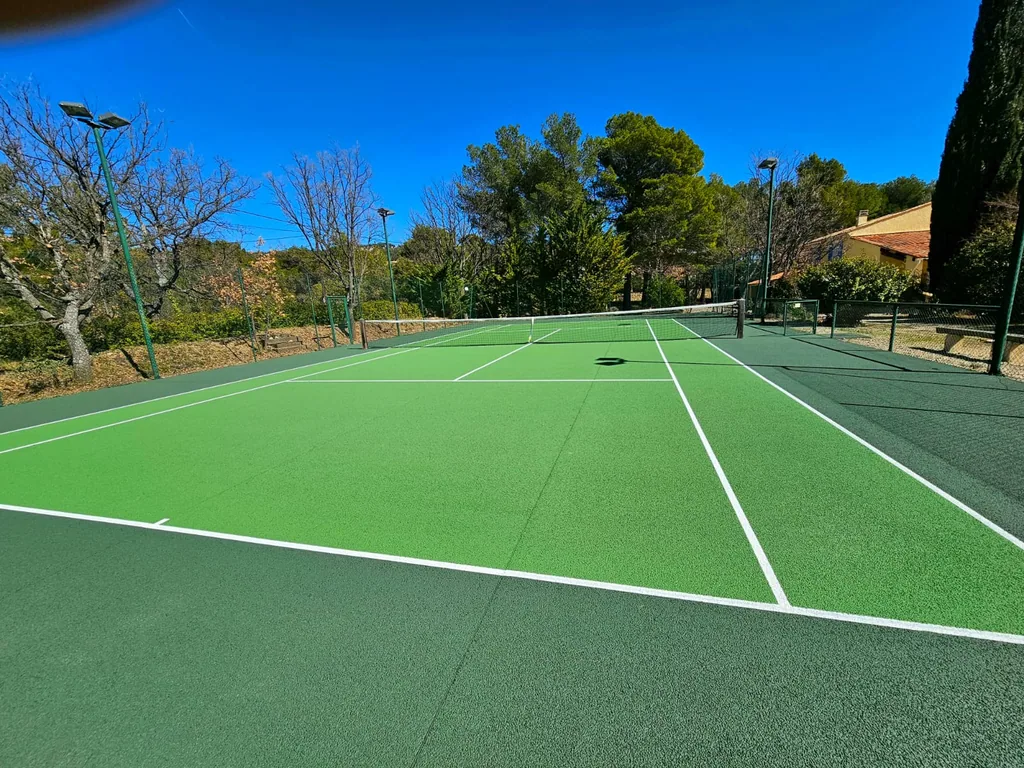 Court de tennis vert clair et vert foncé neuf sous un ciel bleu