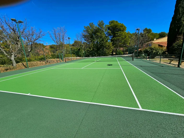 Court de tennis vert clair et vert foncé neuf sous un ciel bleu