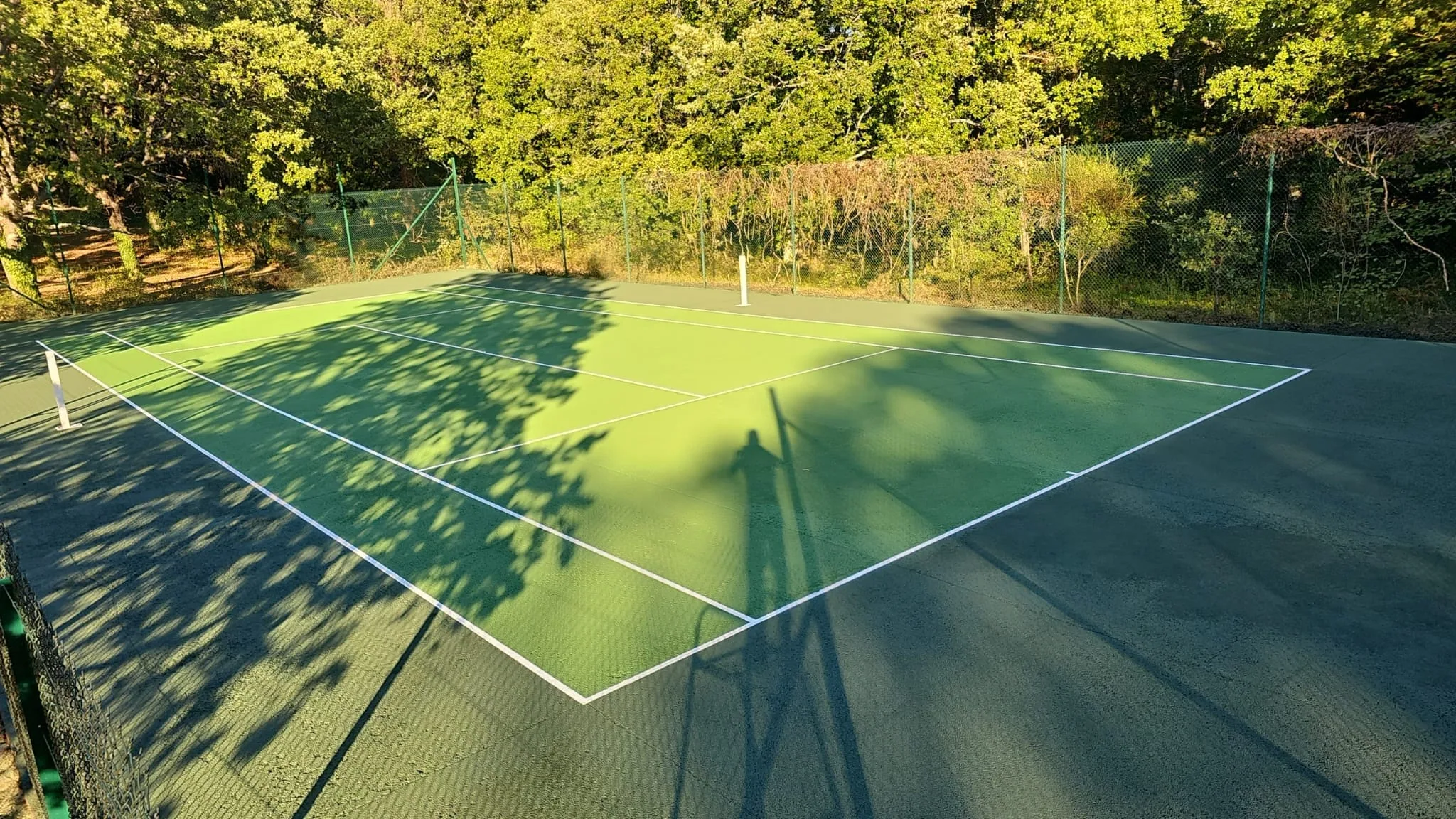 Court de tennis vert éclairé par le soleil couchant