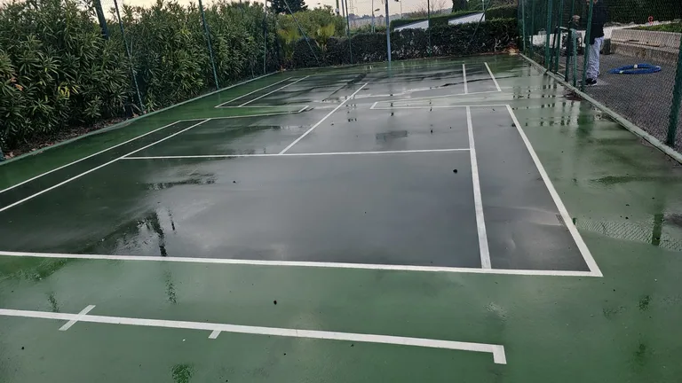 Court de tennis vert foncé détrempé après nettoyage
