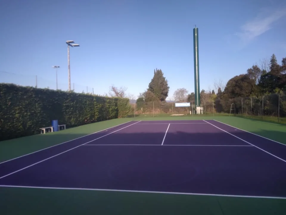 Court de tennis violet et vert éclairé par des projecteurs