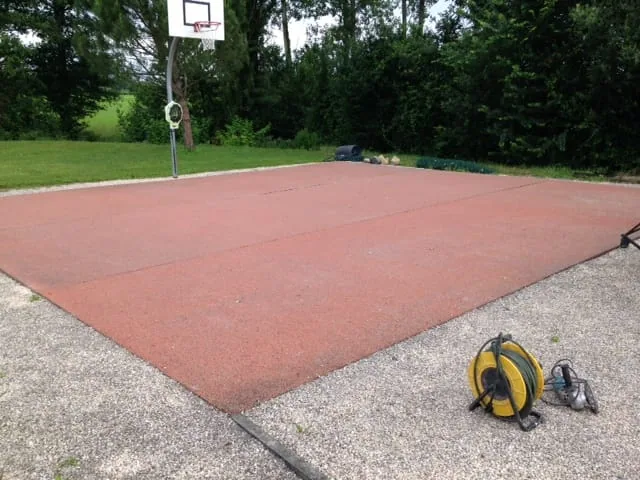 Court en cours de nettoyage haute pression, panier de basket en arrière-plan