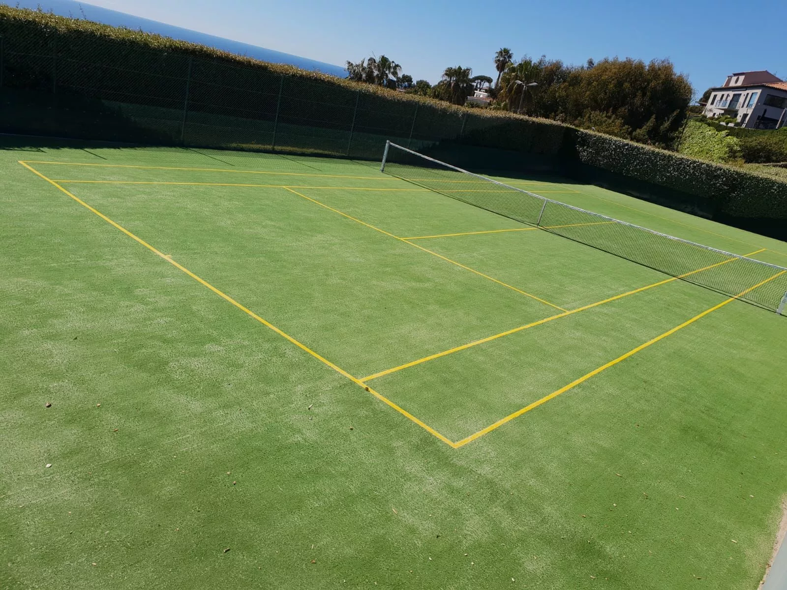 Court en gazon synthétique vert avec lignes blanches et jaunes