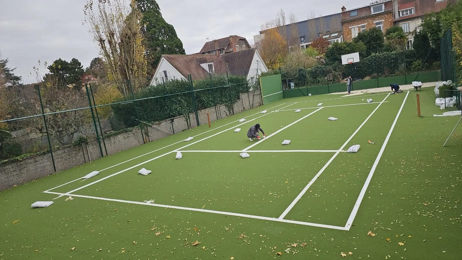Court en gazon synthétique vert d'un jardin en cours de traçage