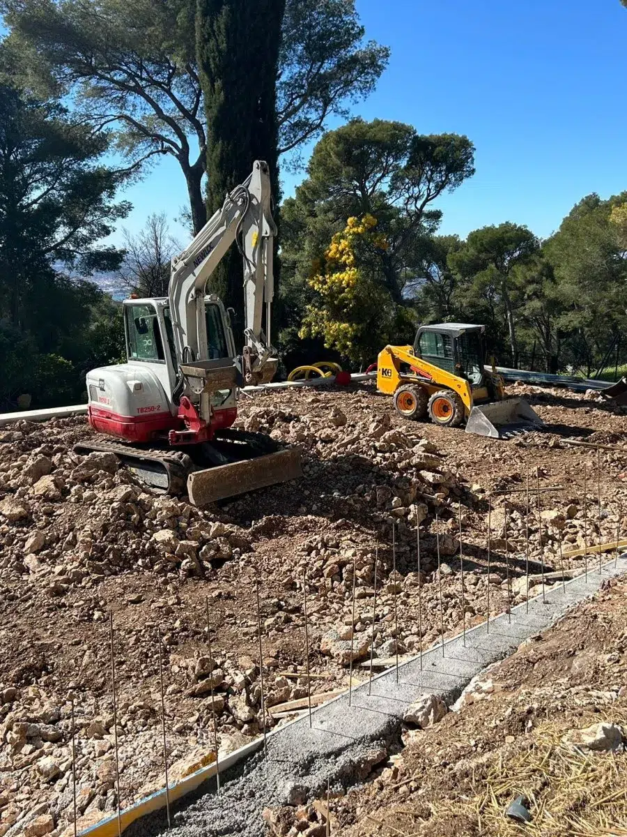 Mini-pelle terrassant un terrain arboré pour un court