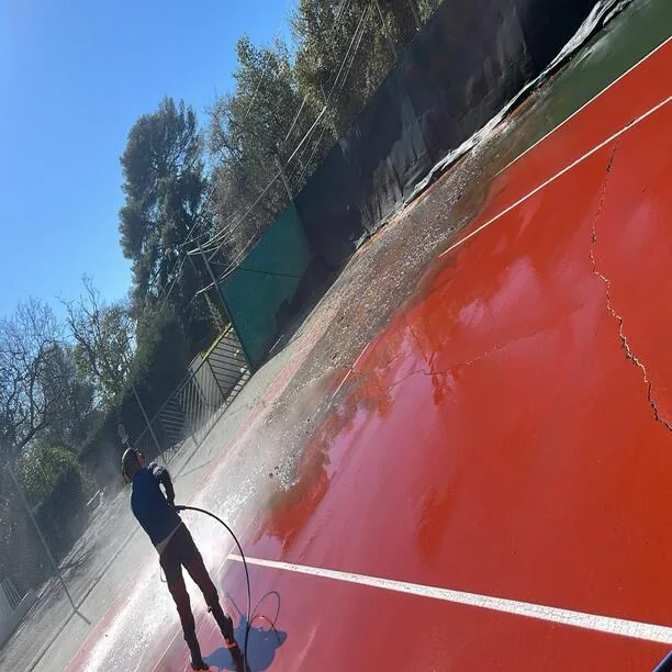 Ouvrier appliquant la peinture rouge sur un court de tennis