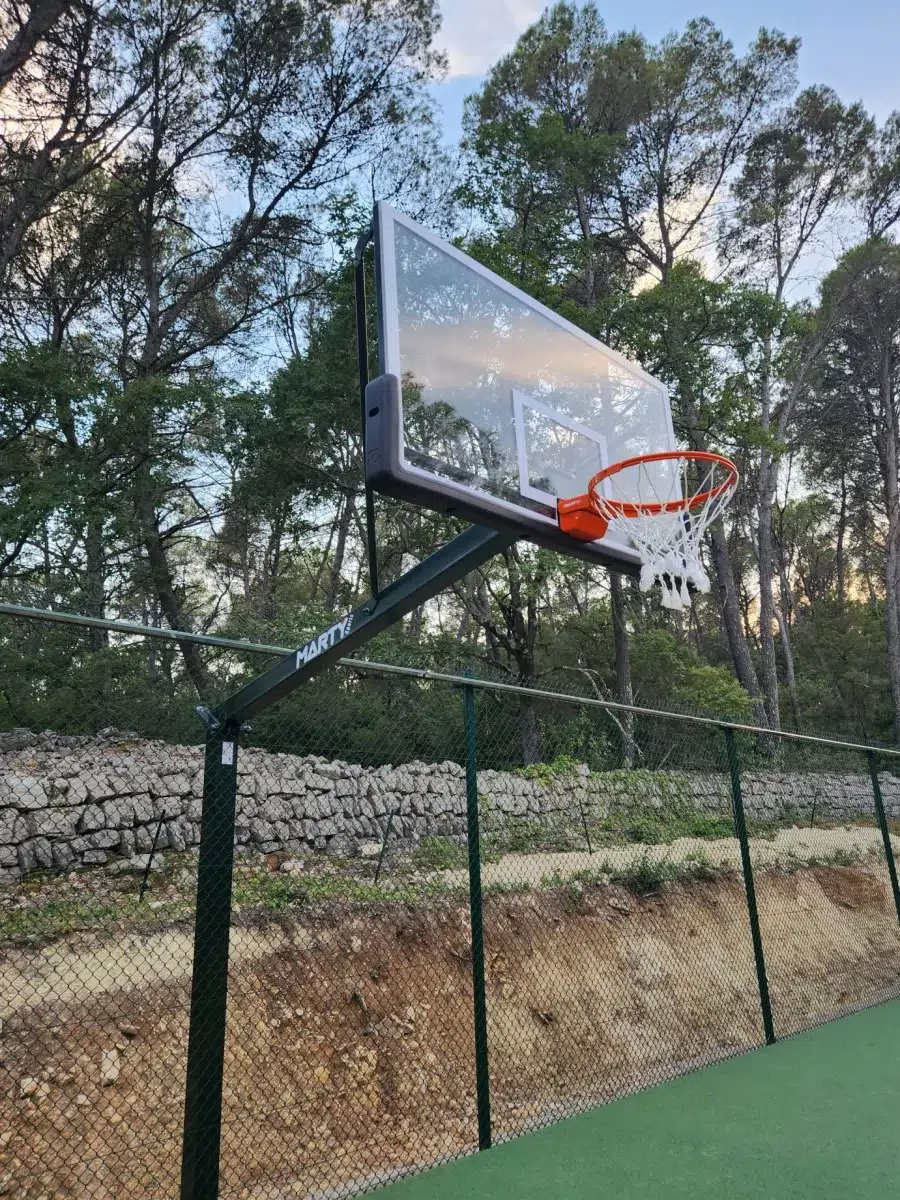 Panier de basket au bord d'un plateau sportif sous les pins