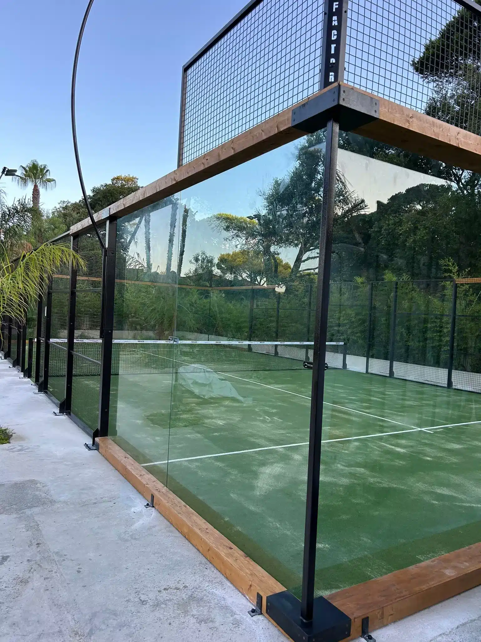 Paroi vitrée d'un terrain de padel au soleil