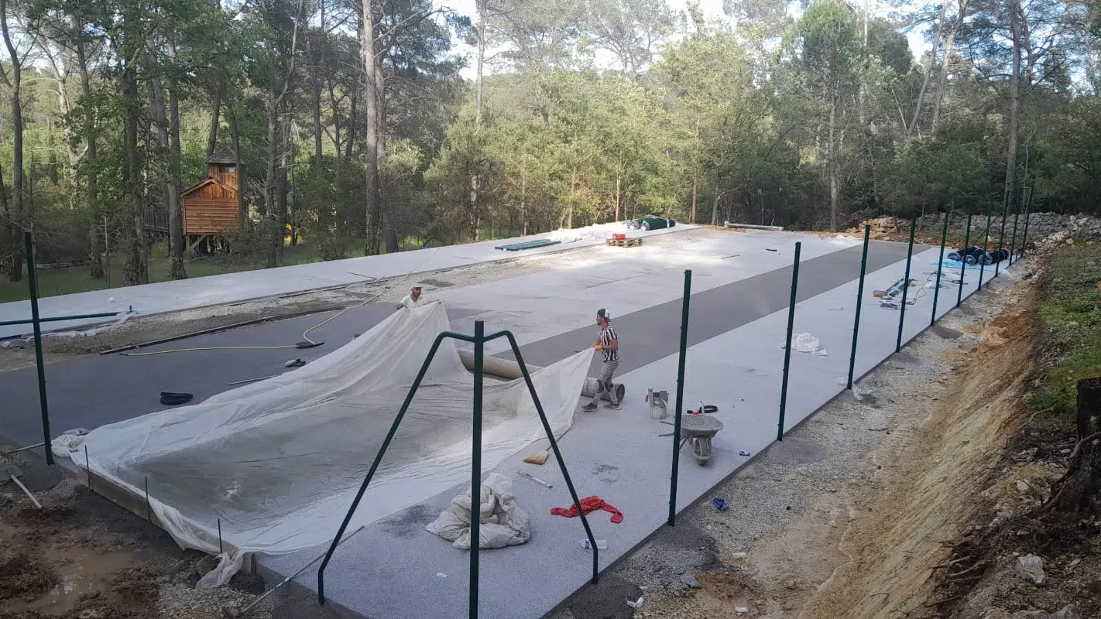 Pose de la clôture autour d'un court en construction