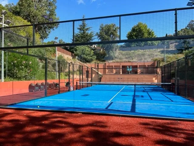 Terrain de padel bleu vitré à abords rouges