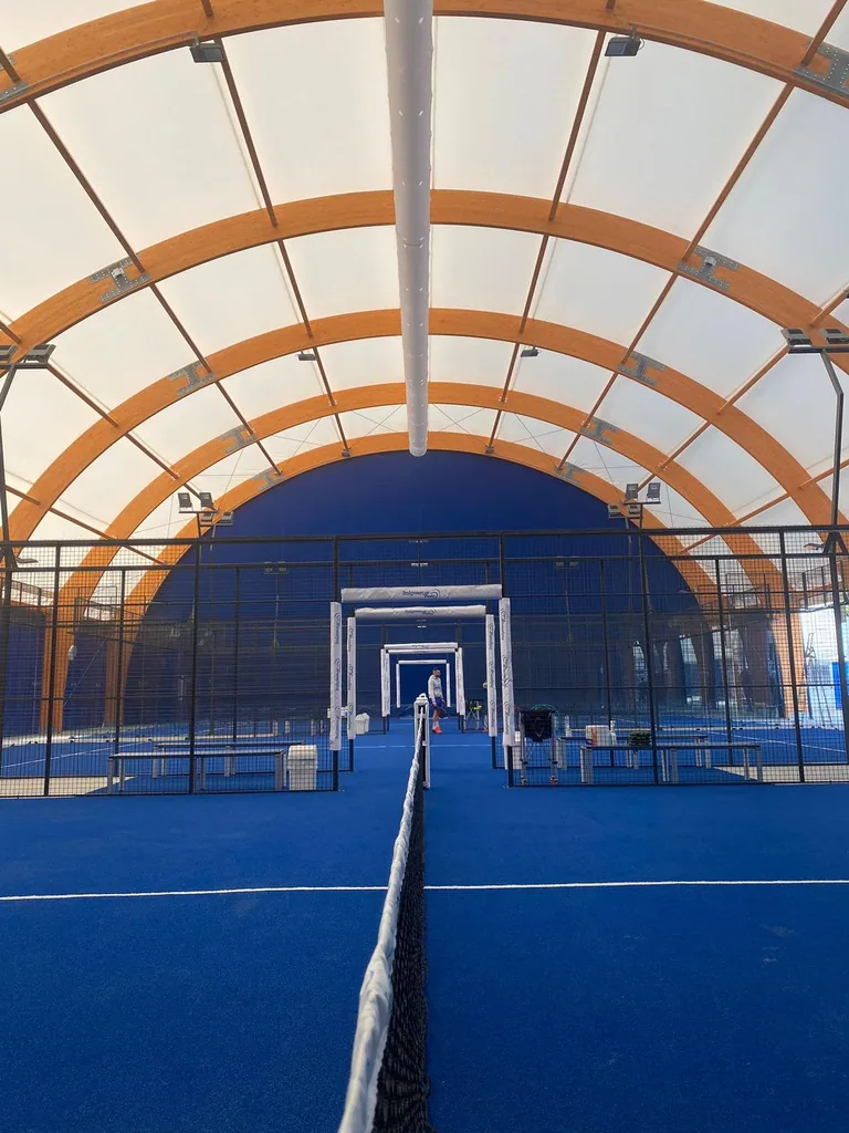 Terrains de padel bleus sous une couverture à arches en bois